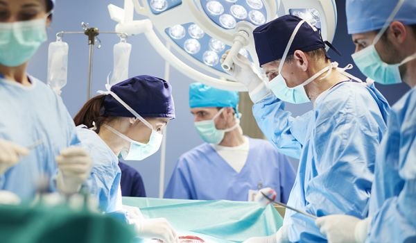 Surgeons in an operating room looking at a patient during surgery.
